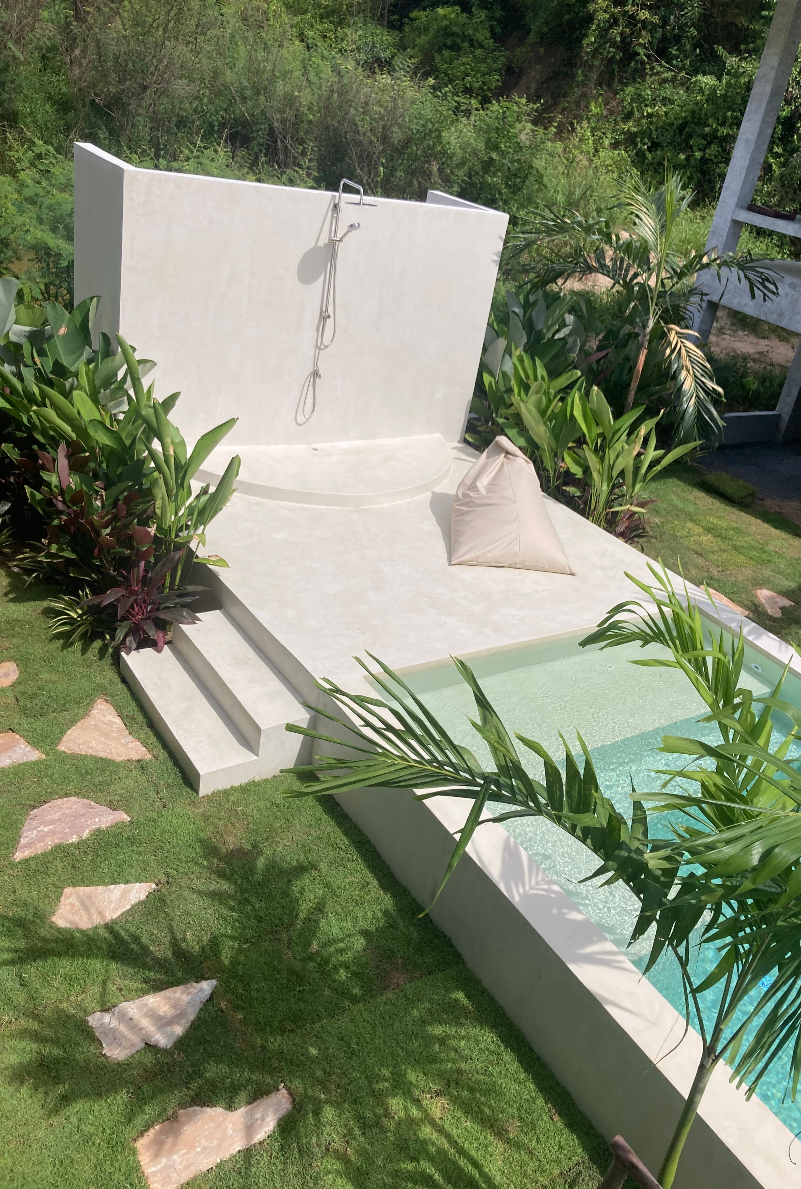 Pool lounge area with outdoor shower and tropical plants